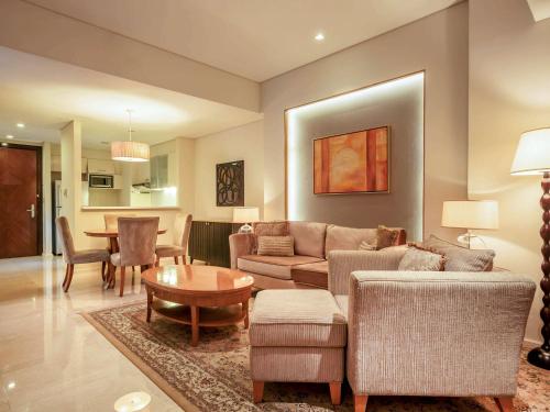 Joy-Nostalg Hotel & Suites Manila Managed by AccorHotels في مانيلا: غرفة معيشة مع أريكة وطاولة