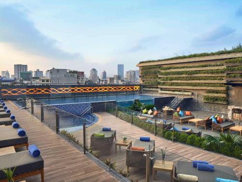 Novotel Hanoi Thai Ha في هانوي: مسبح على طاولات وكراسي في مبنى