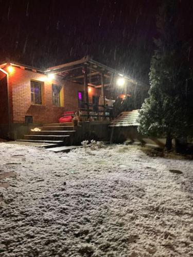 a log cabin in the snow at night at Cottage House Official in Niš