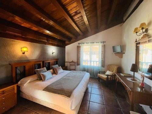 a bedroom with a large bed and a desk and chair at Posada Real de Carreteros in Casarejos