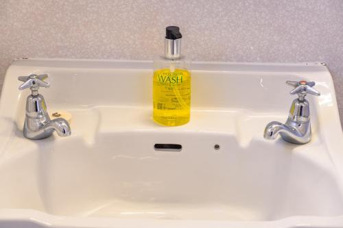 - un lavabo blanc dans la salle de bains avec une bouteille de savon jaune dans l'établissement Burkes Pass Country Motels, à Burkes Pass