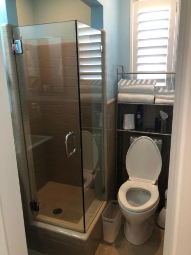 a bathroom with a toilet and a glass shower at Private bedroom & den suite with shared pool & tropical garden in Fort Lauderdale