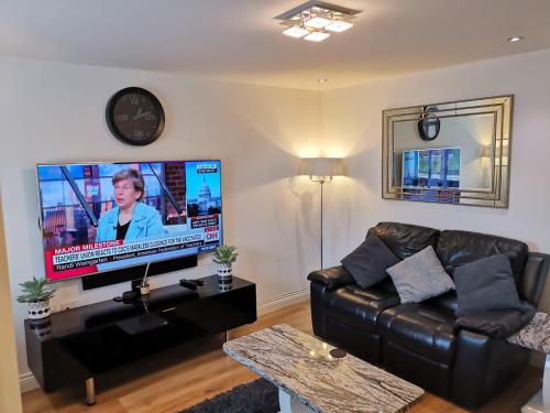Kent的住宿－Langley Haven - 3 BR House，客厅配有黑色真皮沙发和平面电视。