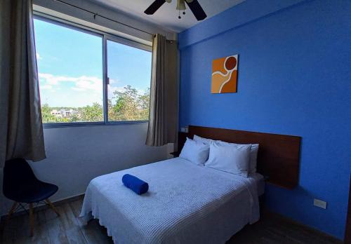 a blue bedroom with a bed and a window at MODERNO DEPARTAMENTO EN EL CENTRO in Tulum