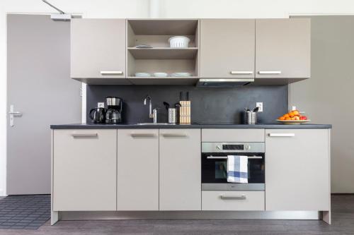 a white kitchen with white cabinets and an oven at Charming Retreat Cozy Family Apartment-20B in Delft