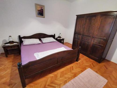 Un dormitorio con una gran cama de madera con sábanas moradas. en Apartments with parking space Seget Vranjica, Trogir - 16661, en Donji Seget