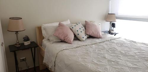 una camera da letto con un letto con cuscini rosa e bianchi di Departamento en Bosques de Montemar a Concón