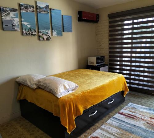 a bedroom with a bed with a yellow blanket on it at LOFT PLAYAS "A" , a unos pasos del malecon estadio acuario y letras in Mazatlán