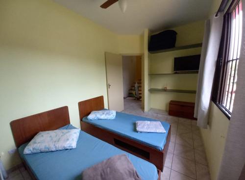 Cette petite chambre comprend deux lits et un bureau. dans l'établissement Recanto da praia, à Bertioga