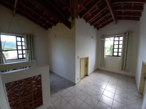 Cette grande chambre dispose de 2 fenêtres et de murs blancs. dans l'établissement Recanto da praia, à Bertioga
