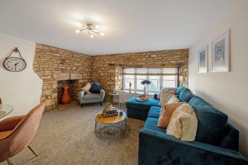 a living room with a blue couch and a stone fireplace at Spacious apartment in 18th Century building, town centre with Smart TV in Cirencester