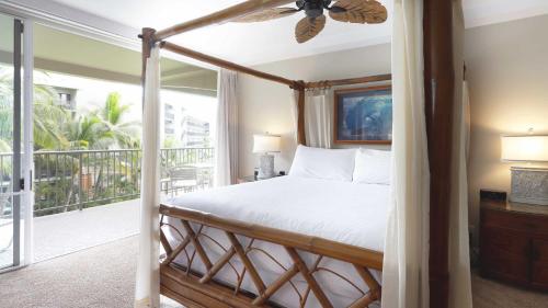1 dormitorio con cama con dosel y balcón en Maui Westside Presents: Whaler 420 - Best location in Kaanapali beach, en Lahaina
