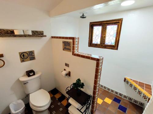 a bathroom with a toilet and a staircase with a window at Hacienda El Galeon in Ensenada