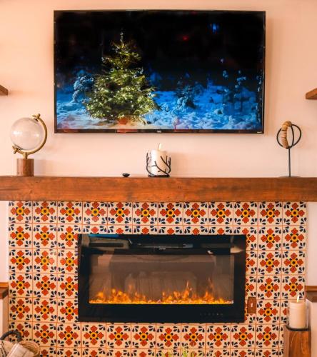 a fireplace with a television above it with a christmas tree at Hacienda El Galeon in Ensenada