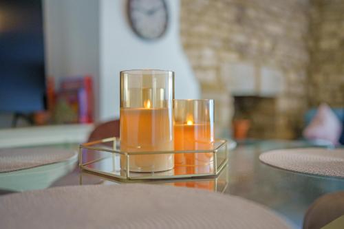 two candles in a glass container on a table at Cotswolds- 2 bed flat in 18th Century building, town centre with Smart TV - Esho Stays in Cirencester