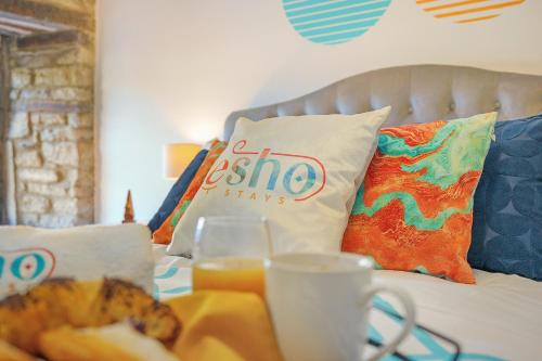 a bed with pillows and a table with a tray of food at Cotswolds- 2 bed flat in 18th Century building, town centre with Smart TV - Esho Stays in Cirencester
