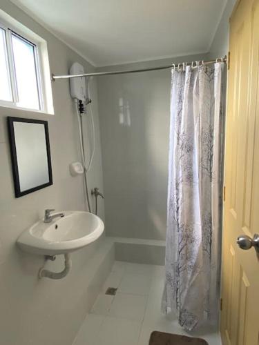 a bathroom with a sink and a shower curtain at Scenic Lake Sunset View in Iloilo City