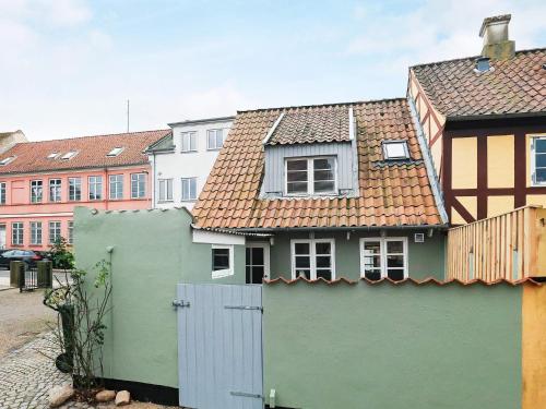 a house with a green fence and buildings at 4 person holiday home in Rudkøbing-By Traum in Rudkøbing