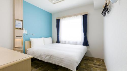 a bedroom with a white bed and a window at Toyoko Inn Nagano-eki Higashi-guchi in Nagano