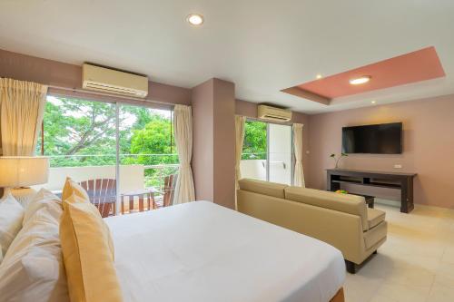 a bedroom with a bed and a couch and a television at Bella Villa Prima in Pattaya