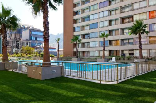 a swimming pool in front of a building with palm trees at Apartment located in midtown in Santiago