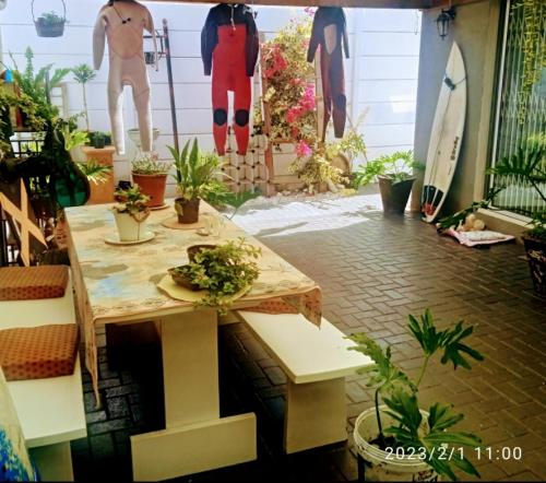een kamer met een tafel met planten en een surfplank bij Zagorski’s Bed and breakfast in Bloubergstrand