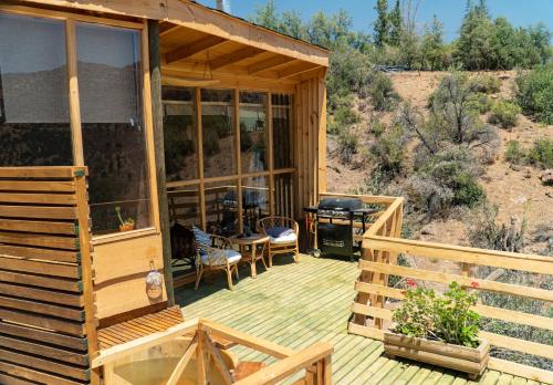 a wooden porch of a cabin with a table and chairs at Origen del Maipo Lodge in San José de Maipo