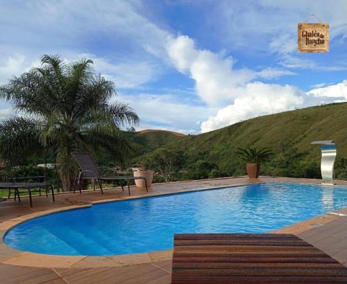 a large blue swimming pool with a mountain in the background at Pousada Chalés do Rancho Canastra in Vargem Bonita