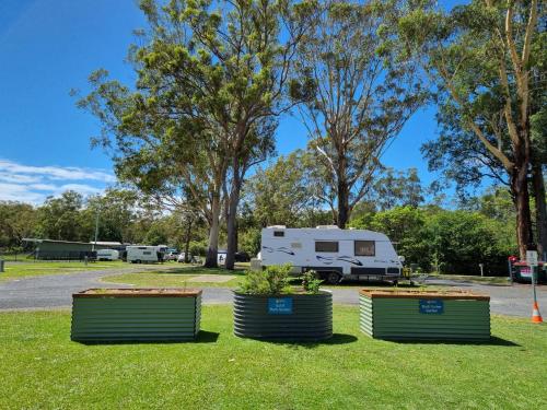two rvs parked in a park with trees at Reflections Coffs Harbour - Holiday Park in Coffs Harbour