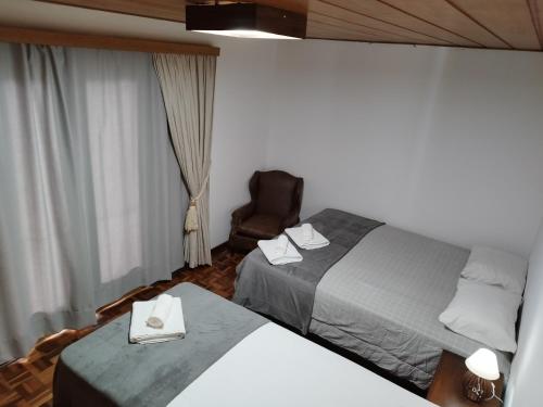 a hotel room with two beds and a chair at Château Capivari - Campos do Jordão in Campos do Jordão