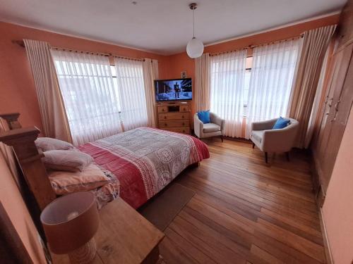 Bonito departamento Sopocachi centro في لاباز: غرفة نوم بسرير وكرسي وتلفزيون