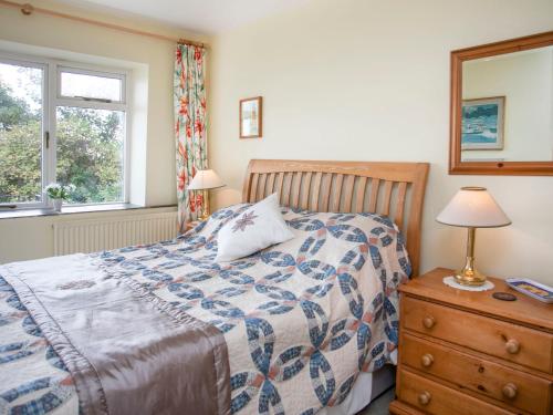 a bedroom with a bed and a dresser and a window at Bwthyn at Brynhyfryd in Pwllheli