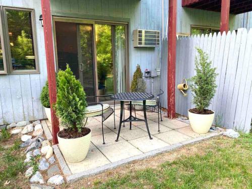 a patio with a table and two potted plants at Attitash Mountain Village Studio - Slope View - Ski - Storyland in Bartlett