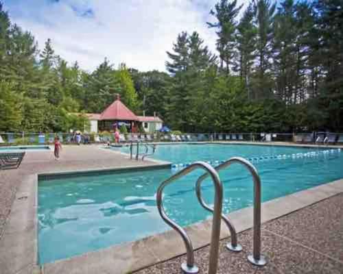una grande piscina con acqua blu e alberi di Attitash Mountain Village Studio - Slope View - Ski - NEWLY RENOVATED a Bartlett