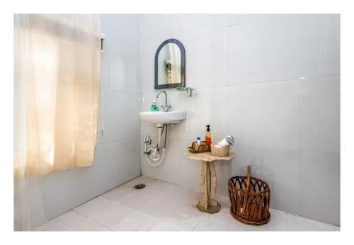 a white bathroom with a sink and a mirror at Tranquility in Shivpurī