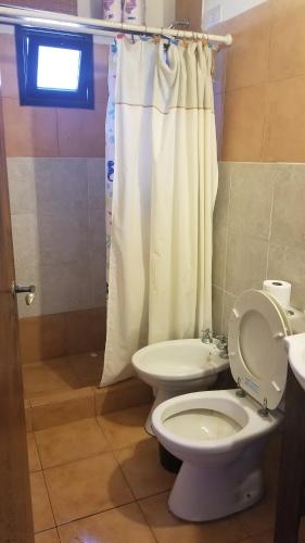 a bathroom with a toilet and a shower curtain at La boyita quinta in General Alvear