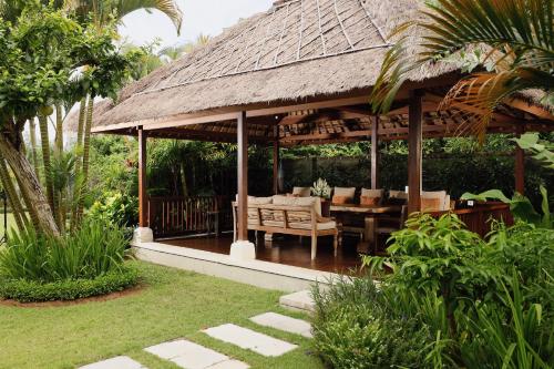 a pavilion with a table and chairs in a garden at Villa Uma Nina by Nakula in Jimbaran