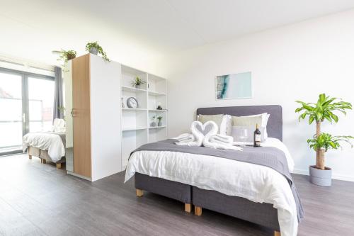 1 dormitorio blanco con 1 cama grande y plantas en Luxurious Loft apt w-View walk city center New Delft Family XL, en Delft