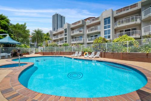 a swimming pool with chairs and a building at Markham Court in Gold Coast