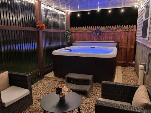 a jacuzzi tub in a patio with chairs and a table at Spacious Pocono Home with Hot Tub and Fire Pit in Long Pond