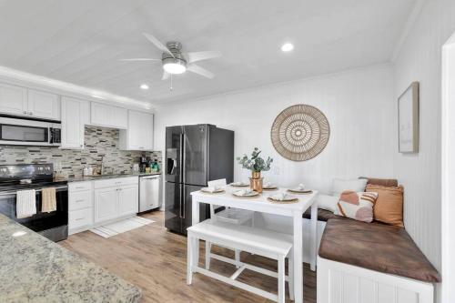 a white kitchen with a table and a refrigerator at * NEW* The Bungalow Jupiter! - Moremoments Rentals in Jupiter