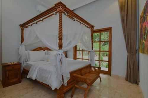 1 dormitorio con cama con dosel y marco de madera en Beachfront Private VILLA & POOL, en Banjar