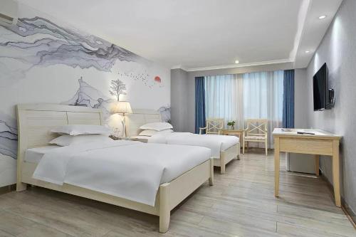 Una habitación de hotel con tres camas y un escritorio. en Cheng yue International Hotel, en Guangzhou