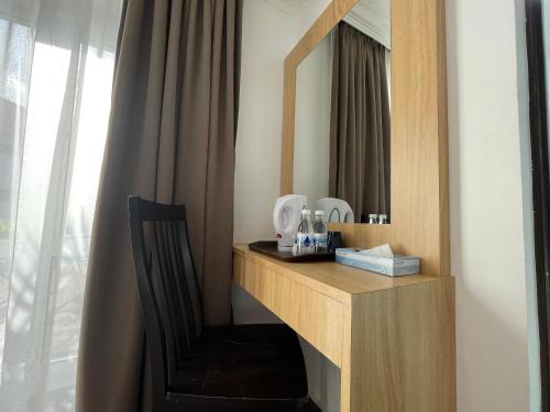 een wastafel met een spiegel en een stoel in de kamer bij DSH Batu Burok Beach Resort in Kuala Terengganu