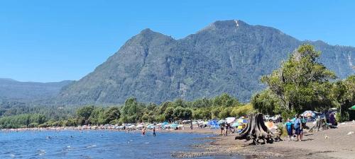 a group of people on a beach with mountains in the background at Coñaripe Kuyen Mapu Cabañas in Coñaripe