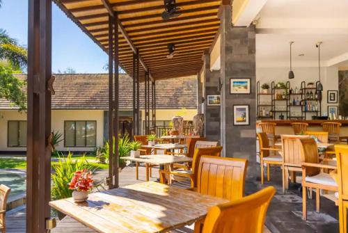 ein Restaurant mit Holztischen und Stühlen in der Unterkunft S Resorts Hidden Valley Bali in Uluwatu