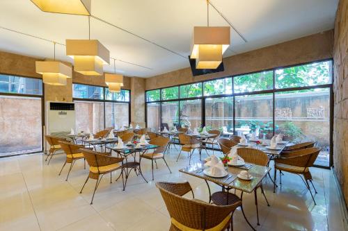 un restaurante con mesas, sillas y ventanas grandes en Bella Villa Prima, en Pattaya central