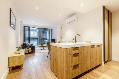 a kitchen with a sink and a living room at KULA South Yarra in Melbourne