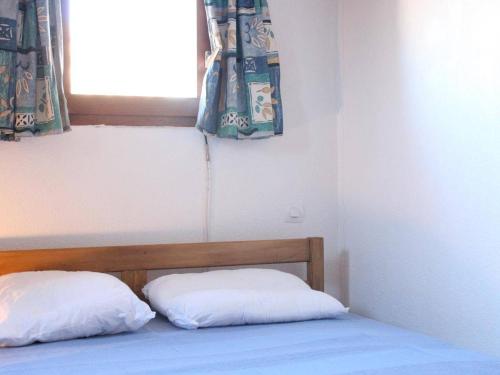 uma cama com duas almofadas num quarto com uma janela em Maison Gruissan, 1 pièce, 4 personnes - FR-1-229-841 em Gruissan