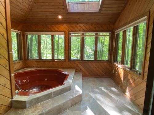 a jacuzzi tub in a cabin with windows at Big House On The Hill in East Stroudsburg